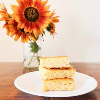 white bean gaps blondies on a white plate with sunflowers in the vase